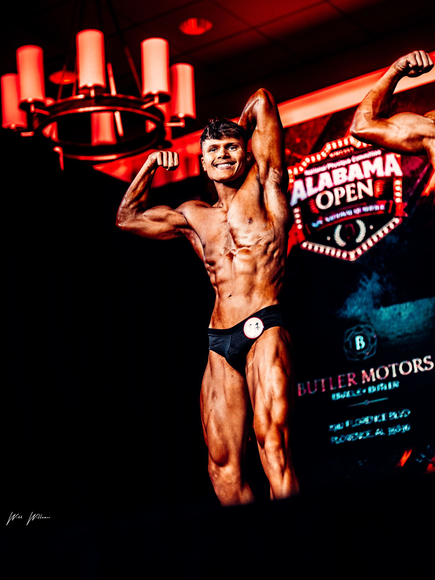 Brenten Brandenburg on stage at the NPC Alabama Open, hitting a front double biceps pose